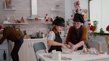 abuela con nieta preparando hecho en casa galletas masa en cocina cuenco Cocinando tradicional Navidad postre durante tiempo de Navidad. contento familia vistiendo delantal disfrutando Navidad Días festivos video