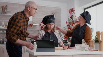 petite fille en train de regarder cuisinier leçon en utilisant tablette ordinateur en train de préparer fait maison pain d'épice pâte en utilisant roulant broche. content famille profiter cuisine Noël dessert célébrer Noël vacances video