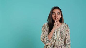 Annoyed indian woman doing shushing hand gesturing, irritated by noise, having negative mood. Person placing finger on lips, doing quiet sign gesture, isolated over studio background, camera A video