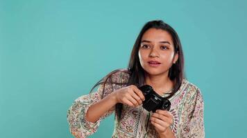 fokuserade kvinna spelar Videospel med rörelse kontrollerade joystick, studio bakgrund. indisk gamer deltar i uppkopplad multiplayer tävlings spel använder sig av gyroskop fungera på gamepad, kamera b video