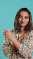 Vertical Portrait of cheerful friendly indian woman smiling, looking pleased, isolated over studio background. Happy person in traditional attire having positive facial expression, feeling satisfied, camera A video