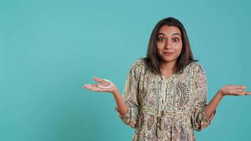 Indian woman shrugging shoulders, unable to provide answer, having detached apathy facial expression. Apathetic person doing hand gesturing showing lack of knowledge, studio background, camera A video