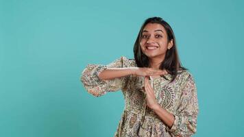 Portrait of assertive indian woman asking for timeout, doing hand gestures, feeling fatigued. Firm person doing vehement pause sign gesturing, wishing for break, studio background, camera A video