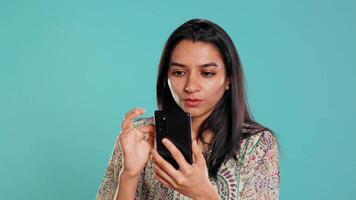 Woman scrolling on smartphone screen, doing online shopping, amazed by beautiful clothes. Portrait of relaxed person browsing internet websites, exclaiming in astonishment, studio background, camera B video