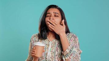 vrouw lijden van slapeloosheid geeuwen, nippen koffie naar krijgen energie en krijgen ontdoen van pijn. moe persoon gevoel slaperig na slapeloos nacht, drinken cafeïnehoudend drank, studio achtergrond, camera b video