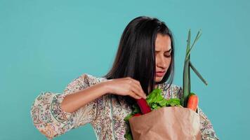 irritato donna accigliato dopo dimenticare per acquistare Tutto quanto, guardare dentro carta Borsa con verdure. consapevole vivente persona broncio dopo rendersene conto alcuni drogheria siamo mancante, telecamera B video