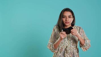 Cheerful woman playing videogames with controller, studio background. Indian gamer smiling, having fun by participating in PvP online multiplayer game using console system, camera A video