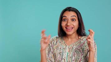 Porträt von optimistisch indisch Frau Kreuzung Finger, Herstellung Wunsch, isoliert Über Studio Hintergrund. lustig bipoc Person in der Hoffnung zum gut Glück, warten zum Wunder, Studio Hintergrund, Kamera b video