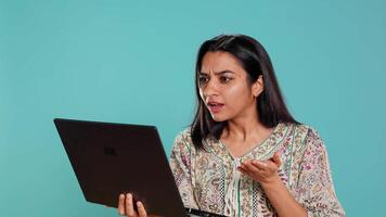 irritado mujer luchando con compañeros de trabajo durante videollamada en computadora portátil, aislado terminado estudio antecedentes. indignado persona discutiendo con colegas durante conversacion en computadora portátil, cámara si video