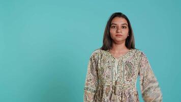 Jolly indian person doing peace victory hand sign gesture, studio backdrop. Portrait of upbeat woman, feeling confident, celebrating win, isolated over studio background, camera A video