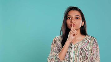 Authoritative woman doing shushing hand gesturing, demanding secrecy, irritated by noise. Stern person complaining, placing finger on lips, doing quiet warning sign gesture, studio background, camera B video