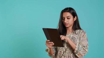 Smiling woman adding payment method on shopping website using tablet, studio background. Jolly person buying online on digital device using credit card, typing data, camera A video