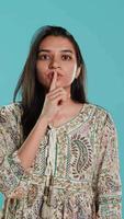 Vertical Authoritative woman doing shushing hand gesturing, demanding secrecy, irritated by noise. Stern person complaining, placing finger on lips, doing quiet warning sign gesture, studio background, camera A video