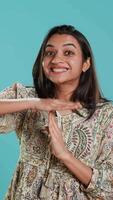 Vertikale Porträt von durchsetzungsfähig indisch Frau fragen zum Auszeit, tun Hand Gesten, Gefühl müde. Feste Person tun vehement Pause Zeichen gestikulieren, wünsche zum brechen, Studio Hintergrund, Kamera ein video