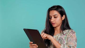 Smiling woman adding payment method on shopping website using tablet, studio background. Jolly person buying online on digital device using credit card, typing data, camera B video