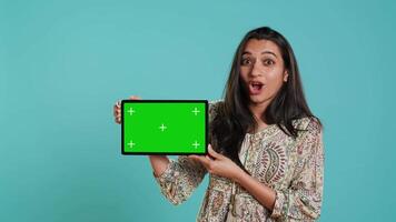 energiek verkoper aan het doen influencer afzet gebruik makend van groen scherm tablet, studio achtergrond. levendig vrouw herzien Product, Holding leeg kopiëren ruimte mockup digitaal apparaat, camera een video