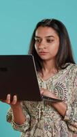 Vertikale indisch Frau Tippen auf Laptop Tastatur und fluchen, Gefühl wütend beim arbeiten. Person Schreiben E-Mails auf Notizbuch, sich beschweren laut, isoliert Über Studio Hintergrund, Kamera ein video