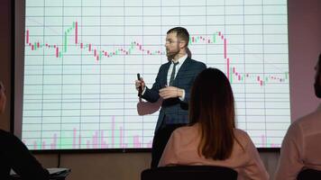 Digital enterpreneur presents cryptocurrency investment strategy for group of investors. Wall TV showing big data analysis, infographics, stock market information, trends video