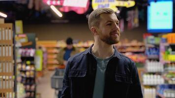 Young man walks at grocery supermarket and choosing the right product video