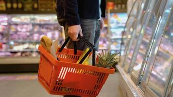 schließen oben von ein Mann mit Einkaufen Korb beim Supermarkt. Mann wählen das richtig Produkt im ein Supermarkt video