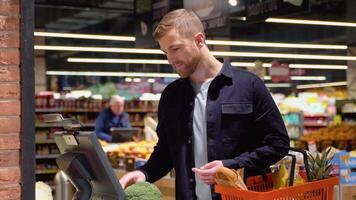 Shopping, sale, consumerism and people concept - young man weighing broccoli on scale at grocery store video