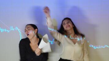 Two funny business woman or traders dance against the background of stock market chart. Traders celebrate a successful deal video