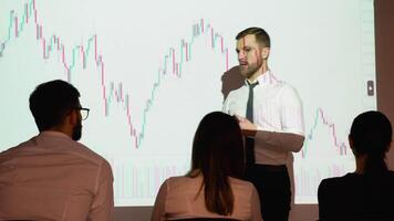 Trader presents stock market investment strategy for group of investors on candlestick chart. Speaker is discussing with participants in the meeting of the prospect of growth or falling stock market video