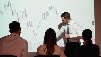 A confident professional business speaker presents cryptocurrency investment strategy for group of investors on candlestick chart video