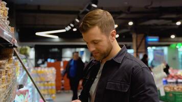 een Mens kiezen verschillend noten in een supermarkt. gezond voedsel concept video