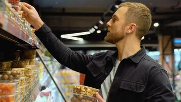 A man choosing different nuts and dried fruit in a supermarket. Healthy food concept video