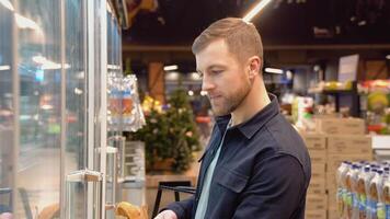 joven hombre compras en lechería sección a supermercado. un hombre haciendo compras a mercado mientras comprando pollo huevos video