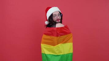 Bearded man with red lips dressed as Santa Claus holding a LGBT flag. Theme of equality and freedom of choice video