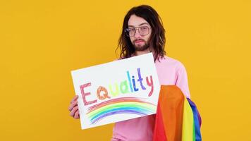 Attractive bearded gay caucasian man holding a protest sign during a LGBT pride parade. Equality concept video