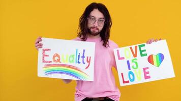attraktiv Gay caucasian skäggig man innehav en protest tecken under en HBTQ stolthet parad. kärlek är kärlek, jämlikhet begrepp video
