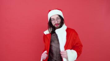 Young smiling happy cheerrful gay man wearing mesh t-shirt and Christmas Santa Claus suit isolated on bright red color background studio portrait. Theme of equality and freedom of choice video