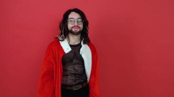 retrato de un transexual hombre en un rojo antecedentes. gay en el traje de Papa Noel noel concepto diversidad, transexual, y libertad video