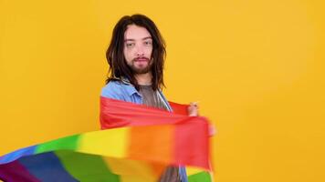 homem segurando arco Iris bandeira lgbt em amarelo fundo. gay orgulho conceito. voto para homossexual amor video