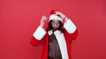 Young smiling happy transsexual gay man wearing mesh t-shirt and Christmas Santa Claus suit isolated on bright red color background studio portrait. Lifestyle lgbtq pride concept video