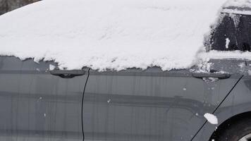 een jong Mens in detailopname reinigt zijn auto na een sneeuwval Aan een ijzig dag. schoonmaak en opruimen de auto van sneeuw Aan een winter dag. sneeuwval, en een erge, ernstige sneeuwstorm in winter video