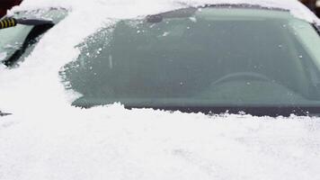 A man cleaning snow from car windshield outdoors on winter day video