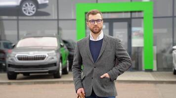 bedrijf, zelfverzekerd elegant Mens staat met een zak in de buurt een auto handel voordat buying een nieuw elektrisch auto video