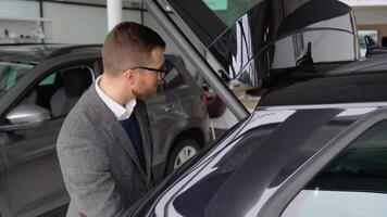 A man closes the trunk of a new electric car in the car dealership. Businessman examine luxury vehicle before making purchase video