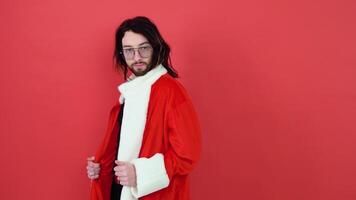 Young smiling happy cheerrful gay man wearing mesh t-shirt and Christmas Santa Claus suit isolated on bright red color background studio portrait. Lifestyle lgbtq pride concept video