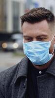 Facial portrait of a man in protective mask. Young handsome man on blur city background. Close-up. Concept of health and safety life. Vertical video