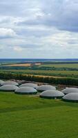 agrícola granja para bio producción. biogás planta en verde naturaleza antecedentes. cámara se mueve adelante. aéreo vista. vertical video