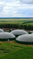 Round storage tanks for biogas. Biogas production on green landscape background. Modern agricultural bio farm on field in summer. Aerial view. Vertical video