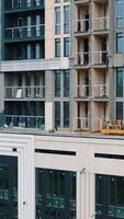 Tall apartment building. Construction of a multi-storey apartment building with windows and balconies. Camera rising up. Vertical video