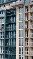 Construction of a modern building in the city. Facade of multistorey apartment house with plastic windows in the city. Building of a new architecture. Vertical video