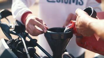 motorcyclists refueling a bike with gasoline from a canister outdoors video