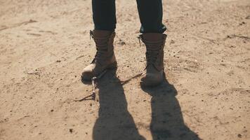 un hombre en botas soportes en el desierto, de cerca video